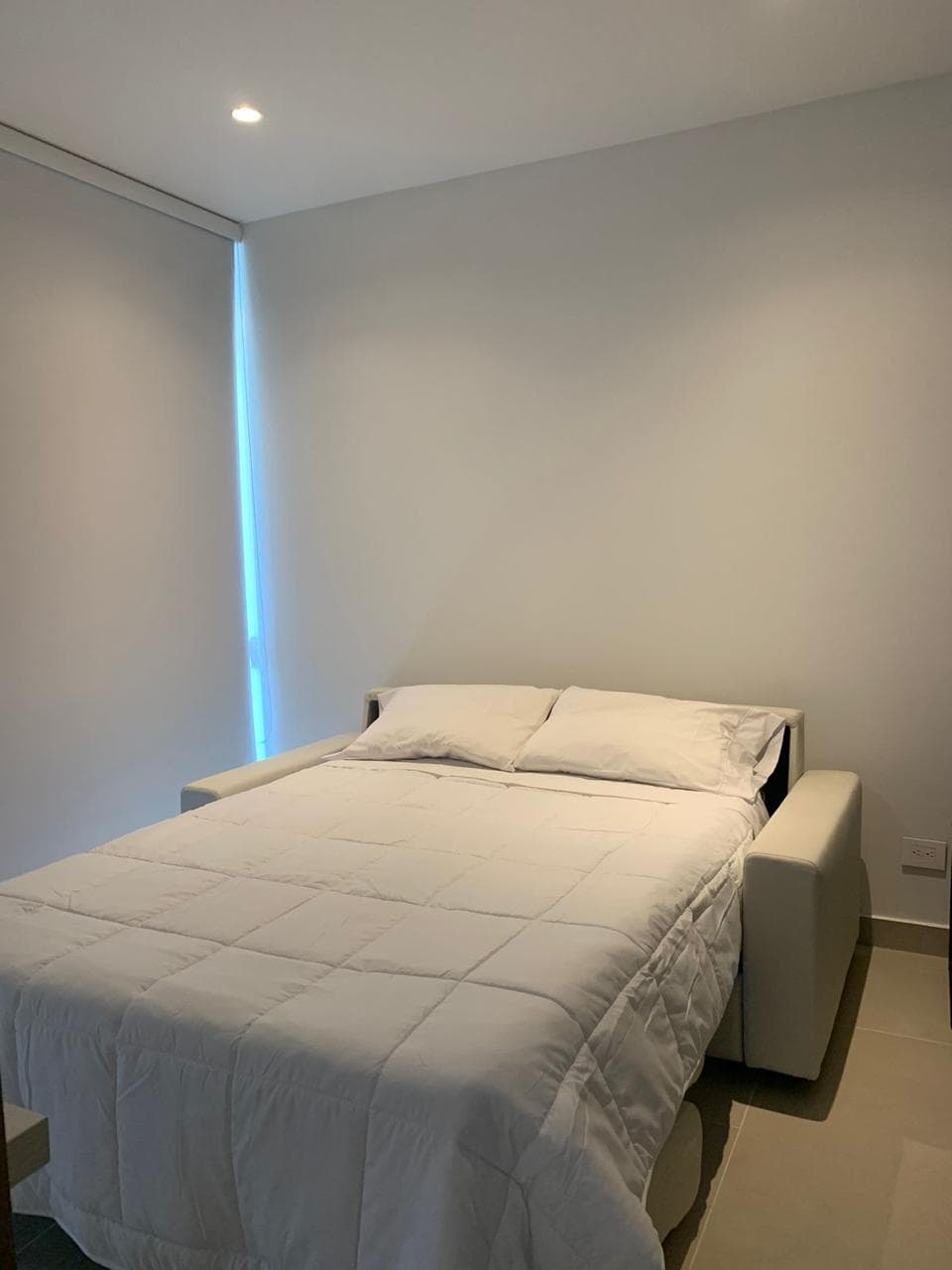Sofá cama italiano abierto en habitación de huéspedes — el colchón está debajo del asiento, sin lomo central