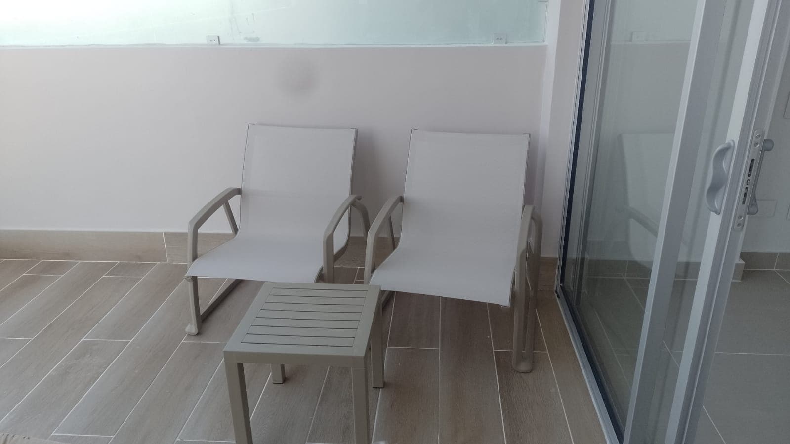 Set de relax con dos sillas blancas y mesa lateral en balcón